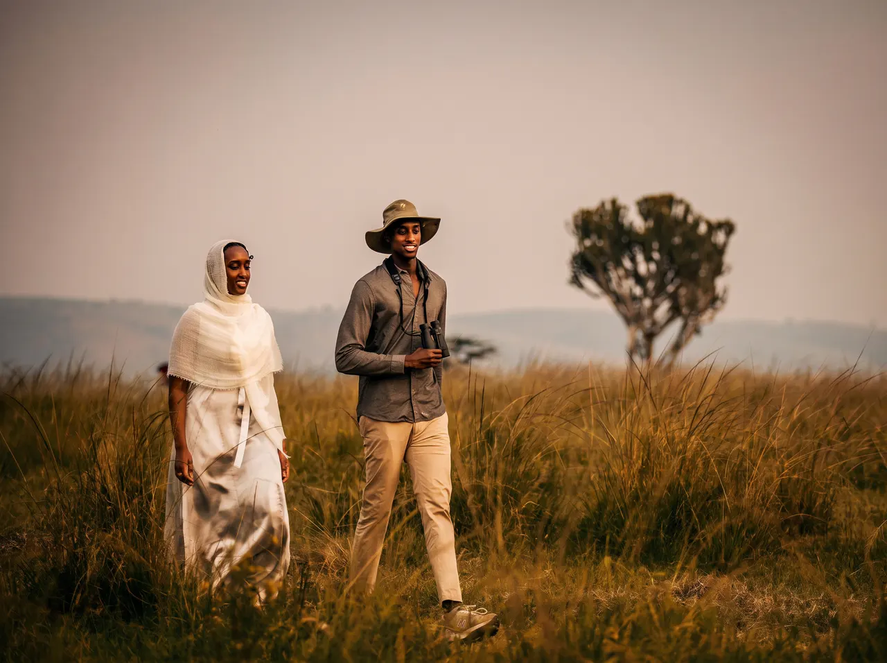 Guests taking a guided nature walk with binoculars through tall grass.
