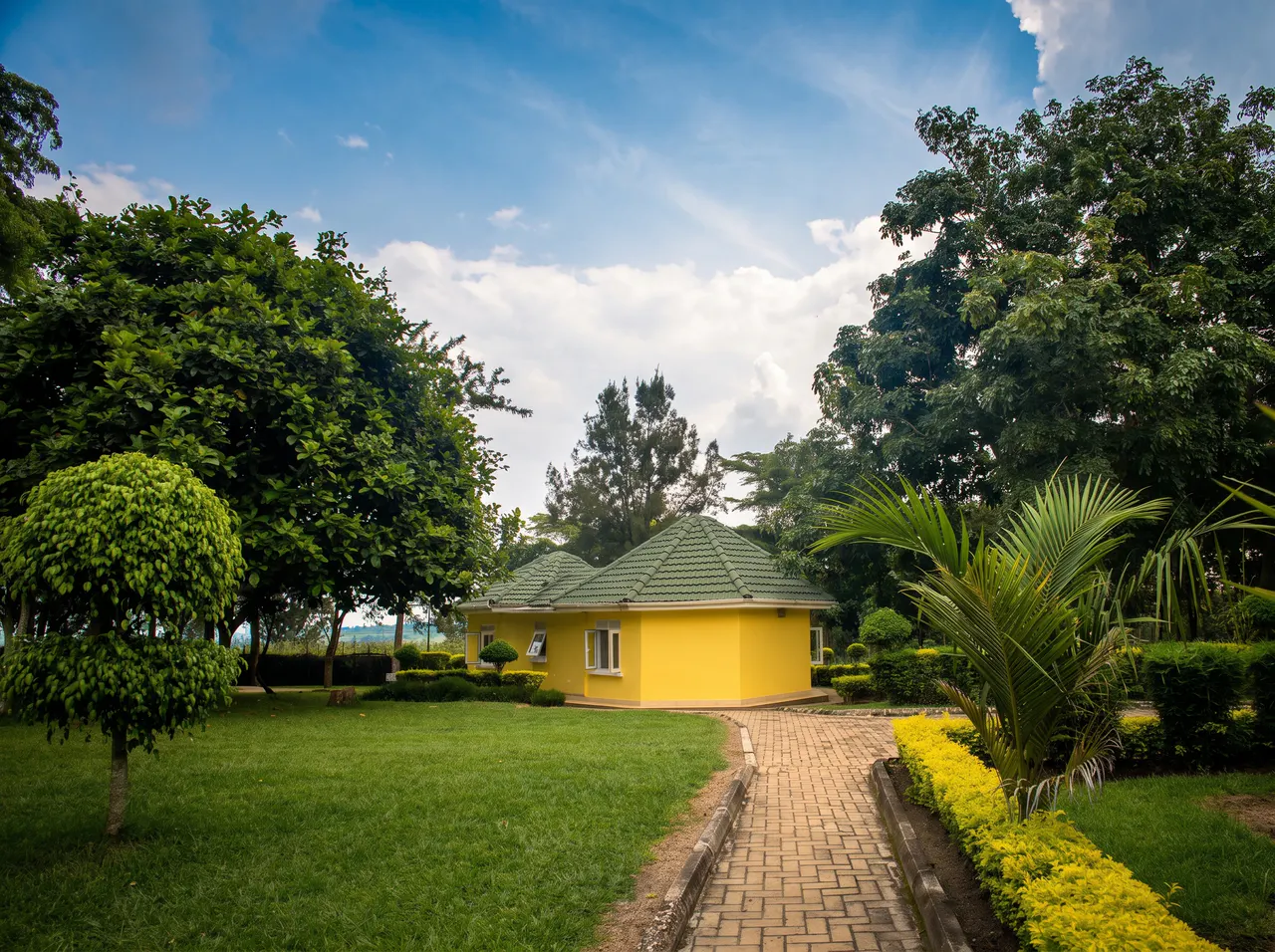 A yellow guest cottage surrounded by landscaped gardens at The Nyakaju.